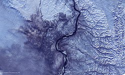 Lena river in ice, Russia  In the east, a handful of streams originate in the mountains of Charaoelach and feed into the river. In the northwest, the Chekanovsky Ridge is home to various types of vegetation and follows the river further downstream to its delta. In the (south)west, clouds or haze obscure the image, though a number of frozen, smaller water bodies (white spots) can be seen.   Date: 06/10/2015   Resolution: 100m : lena, ice, river, russia